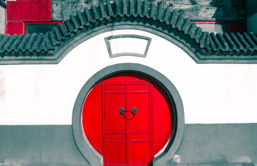 Red circulare Chinese door surrounded by white wall